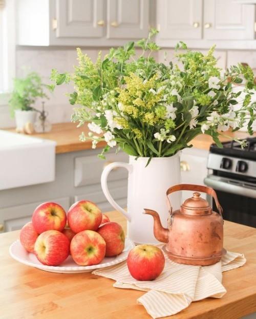 Herbstdeko στην κουζίνα ώριμα μήλα λευκό πορσελάνινο δοχείο με φθινοπωρινά λουλούδια