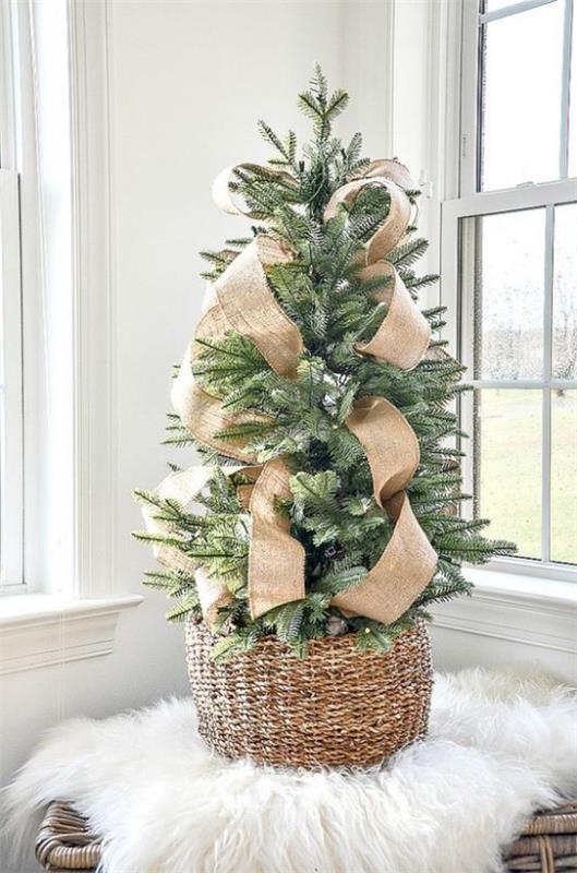 Διακοσμήστε ένα μικρό χριστουγεννιάτικο δέντρο και βάλτε ένα μεγάλο τόξο κάνναβης στο ψάθινο καλάθι