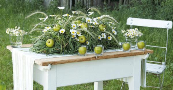 Διακόσμηση τραπεζιού Marguerites έξω από το πράσινο μήλο χόρτο σε ένα παλιό ξύλινο τραπέζι